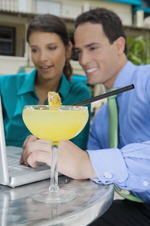 Cocktail in front of Hispanic couple looking at laptopの写真素材