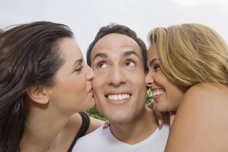 Hispanic women kissing man on cheeksの写真素材