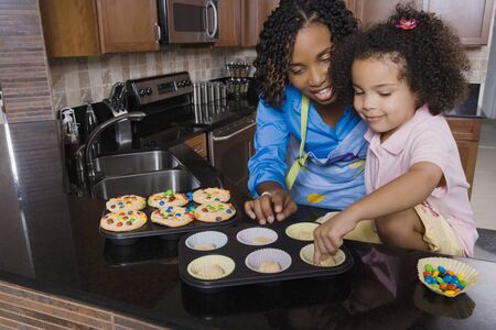 African mother and daughter making cupcakesの写真素材