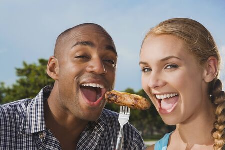 Multi-ethnic couple eating from same forkの写真素材