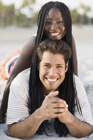 Multi-ethnic couple laying on beachの写真素材