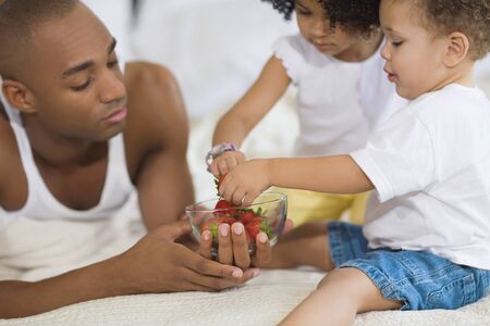 African father and children eating fruitの写真素材