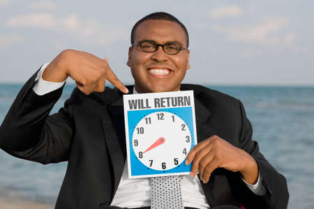 African businessman holding clock signの写真素材
