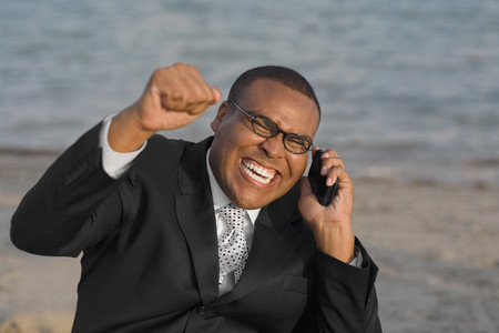 African businessman cheering on cell phoneの写真素材