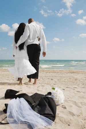 African bride and groom walking on beachの写真素材