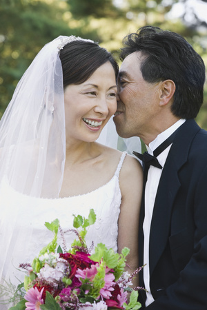 Asian groom telling secret to brideの写真素材