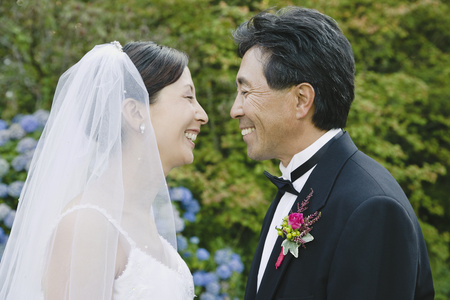 Asian newlyweds smiling at each otherの写真素材