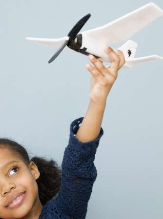 Mixed race girl playing with toy airplane