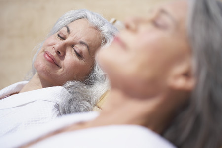 Friends sleeping on lounge chairs at resortの写真素材