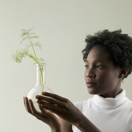 Young woman holding a plant growing in a glass flaskの写真素材