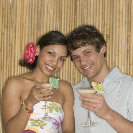 Young couple holding cocktails looking at cameraの写真素材