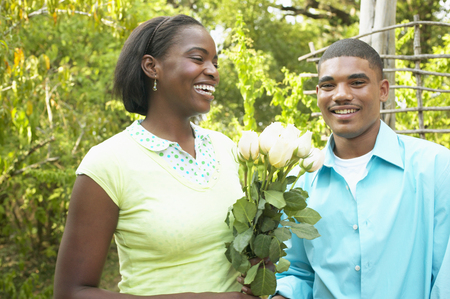 Young couple standing together holding a bunch of flowersの写真素材