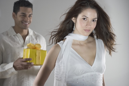 Portrait of a young man standing behind a young woman holding a giftの写真素材