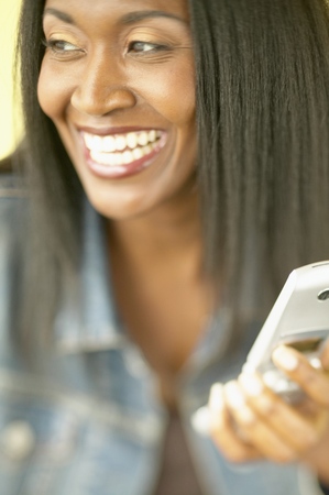 Mid adult woman smiling holding a mobile phoneの写真素材