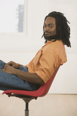 Young man sitting on a chair looking at cameraの写真素材