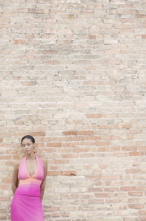 Young woman in front of a brick wallの写真素材