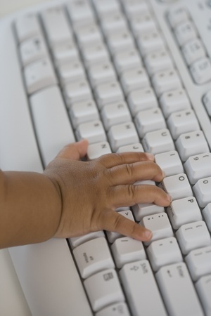 Close up of Hispanic babyÃ¢â¬â¢s hand on computer keyboardの写真素材