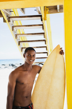 Smiling African man holding surfboard
