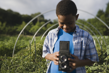 African boy holding retro camera in gardenの写真素材