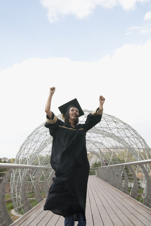 Mixed race graduate in cap and gown cheeringの写真素材