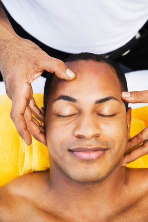 Mixed race man receiving head massageの写真素材