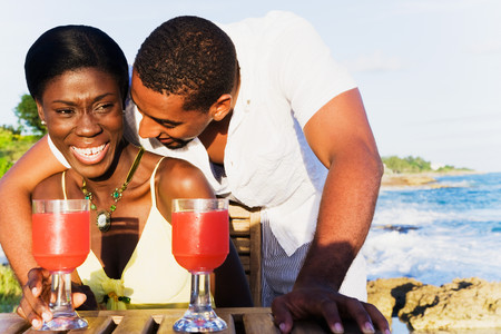 African couple drinking cocktails on patio overlooking oceanの写真素材