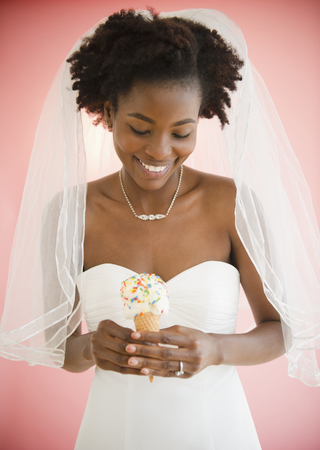 Black bride in wedding dress holding ice cream coneの写真素材