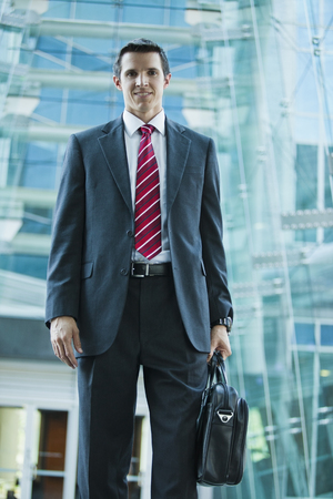 Caucasian businessman holding briefcase outdoorsの写真素材