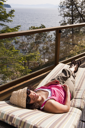 Hispanic woman laying on deck chair sunbathingの写真素材