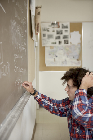Caucasian student writing on blackboardの写真素材