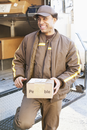 Smiling Hispanic delivery man holding cardboard box
