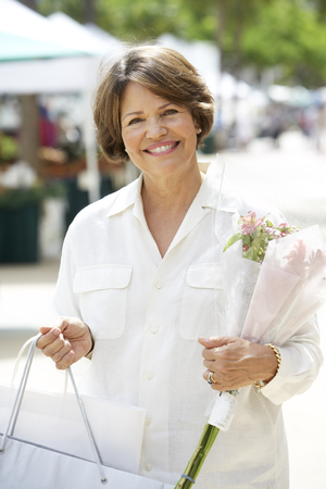 Hispanic woman carrying bouquet and shopping bagの写真素材