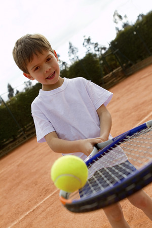 Hispanic boy balancing tennis ball on racquetの写真素材
