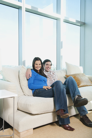 Smiling couple sitting on sofaの写真素材