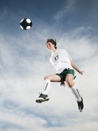 Caucasian teenager heading soccer ball in mid-airの写真素材