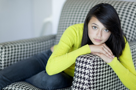 Serious Asian girl sitting in armchairの写真素材