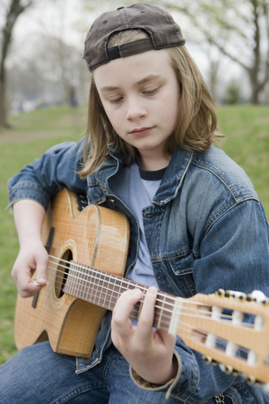 Caucasian boy playing acoustic guitarの写真素材