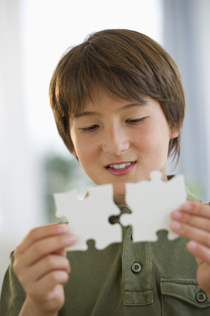 Mixed race boy connecting jigsaw piecesの写真素材