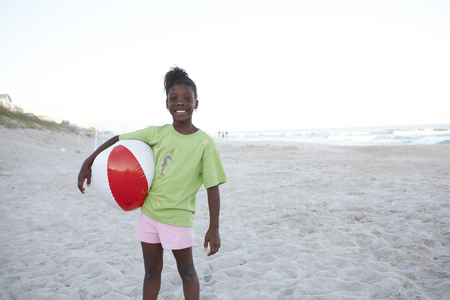 Jamaican girl holding ball on beachの写真素材