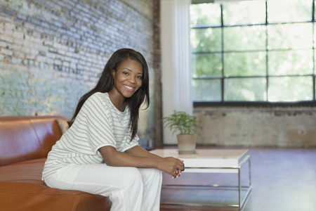 Black woman sitting on sofa in living room