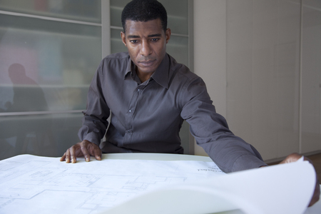 Black businessman reviewing blueprintsの写真素材