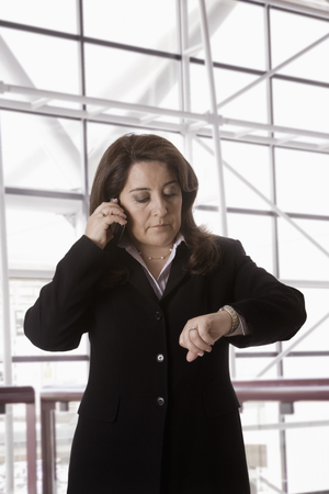 Hispanic businesswoman talking on cell phone checking the timeの写真素材