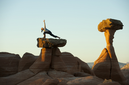 Caucasian woman practicing yoga on top of rock formationの写真素材