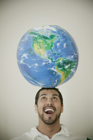 Smiling man balancing globe in his headの写真素材