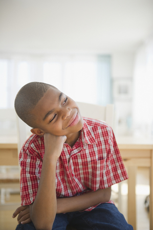 African American boy sitting with head in hands thinkingの写真素材