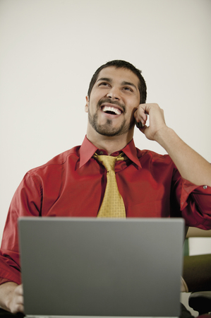 Businessman with laptop talking on cell phoneの写真素材