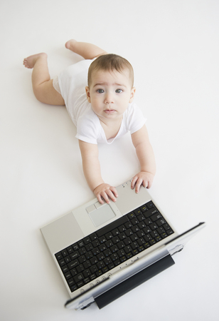 Mixed race baby boy playing with laptopの写真素材