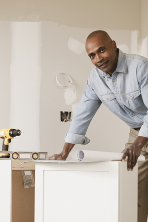 African American man looking at blueprints in unfinished roomの写真素材