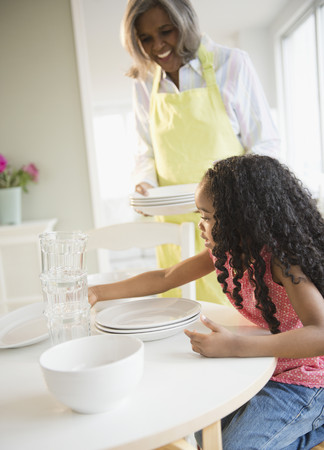 African American grandmother and granddaughter setting the tableの写真素材