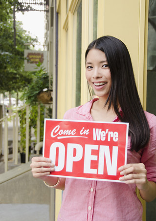 Asian woman holding open sign
